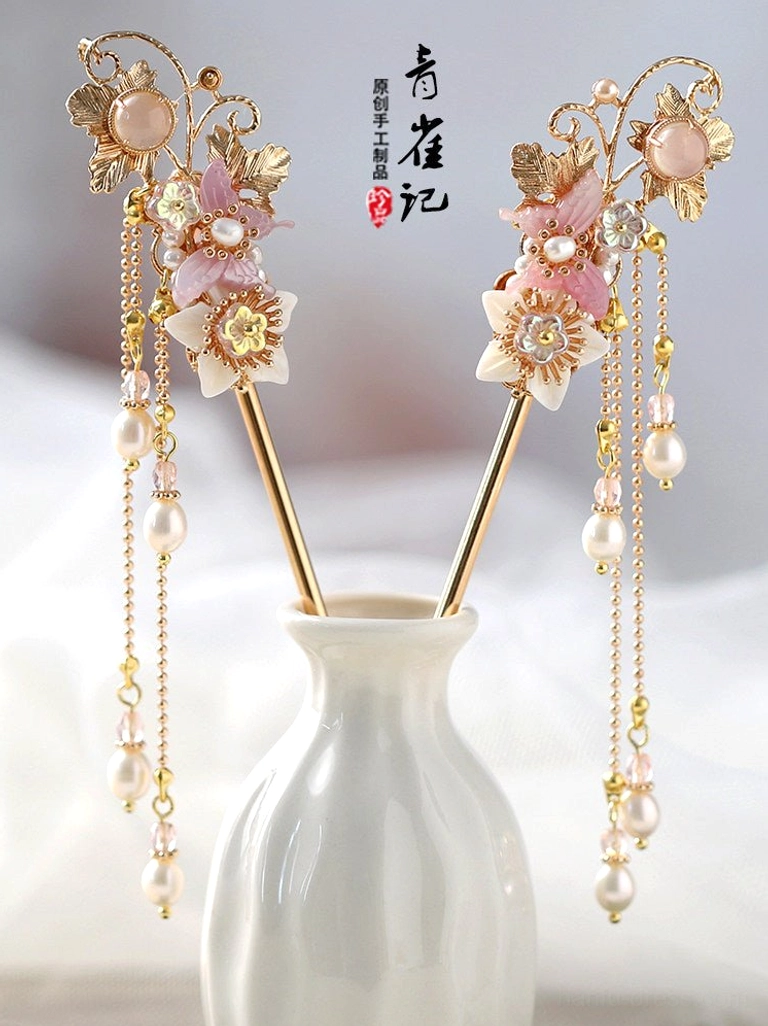 Floral Chinese hair stick pair displayed in a ceramic vase with gold accents pink flowers and pearl chain tassels