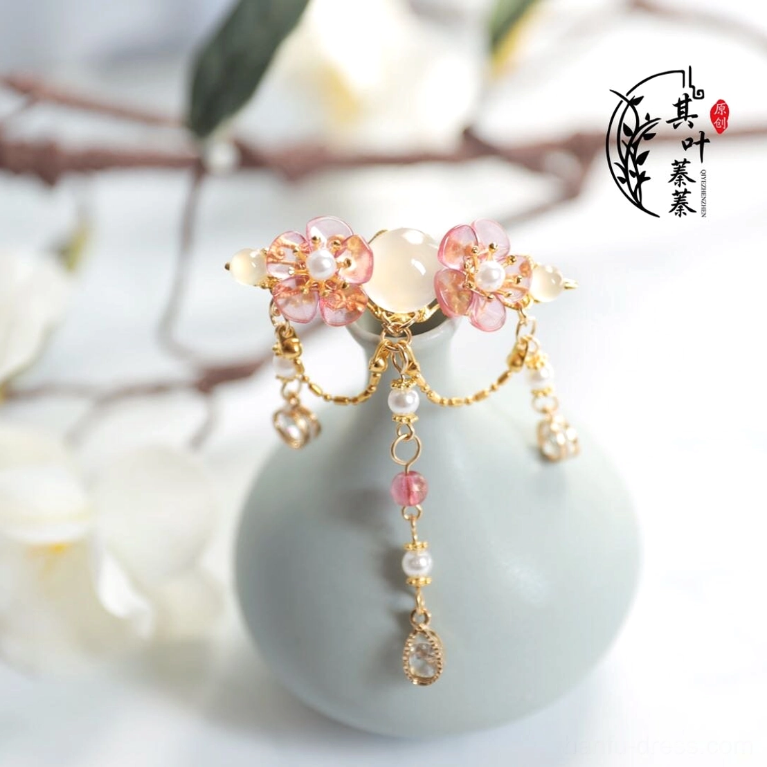 Close view of floral Hanfu forehead hair ornament with central white round stone style detail, pink flowers, pearl like beads and dangling gold tone tassels