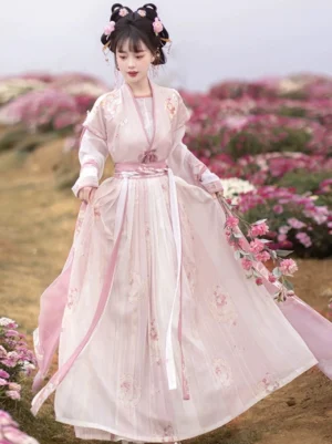 Front full body view of a floral Tang Dynasty style Qiyao Ruqun Hanfu set with pink beizi half sleeve top, ivory inner garment, flowing ribbons, and long printed skirt in a blooming flower field