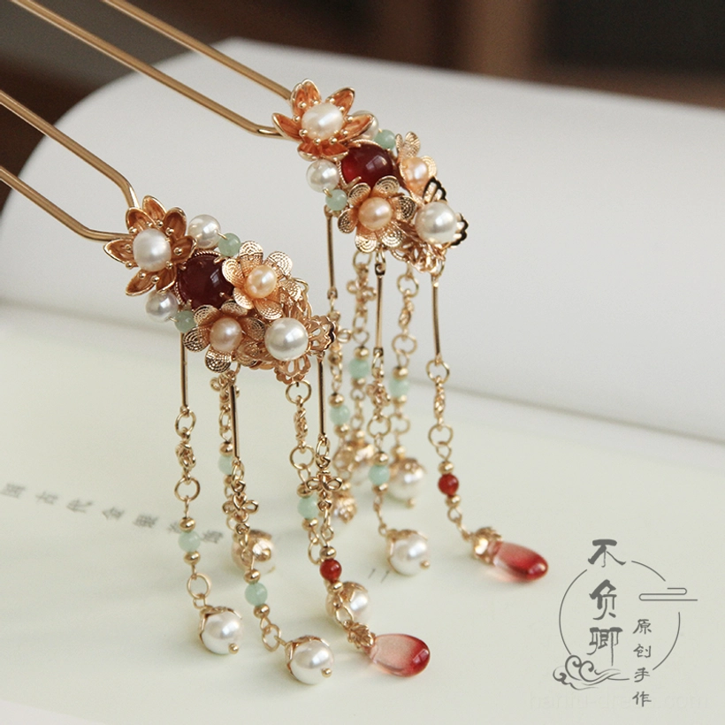 Flower Festival Chinese hair stick with warm gold-tone floral ornament faux pearls burgundy beads red teardrop pendant and delicate tassels displayed on a vintage book