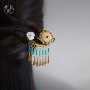 Flowing jade Chinese hair stick worn in dark hair with shell flower turquoise bead tassels and gold-colored pendants