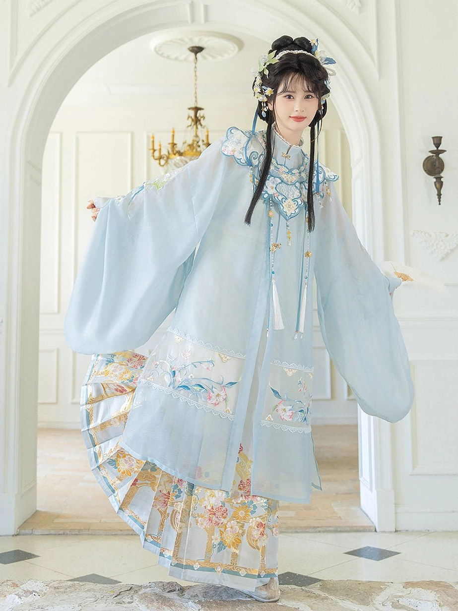 Woman spinning in a flowing Ming Dynasty hanfu set with pale cyan robe, floral landscape embroidery, and elegant ivory Mamian skirt