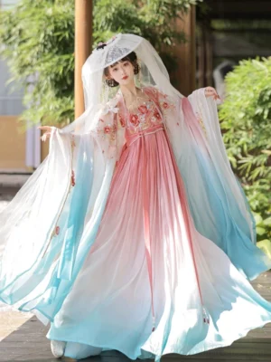 Flying Flower Tang Dynasty Hanfu Heziqun dress in pink and cyan gradient with floral embroidery, wide sleeves, and floor length skirt worn outdoors