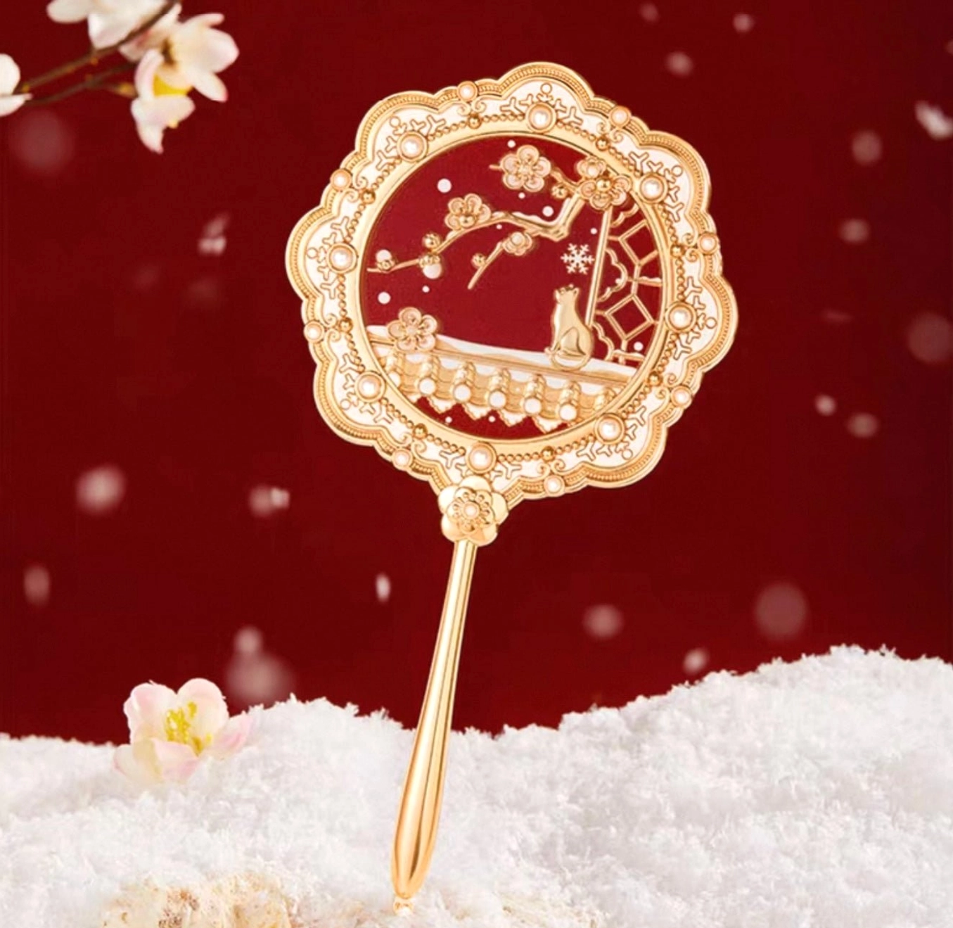 Forbidden City Snow plum blossom cat Chinese hand mirror with deep red mirror panel, gold scalloped frame, faux pearl details, and slender handle displayed against a snowy festive background