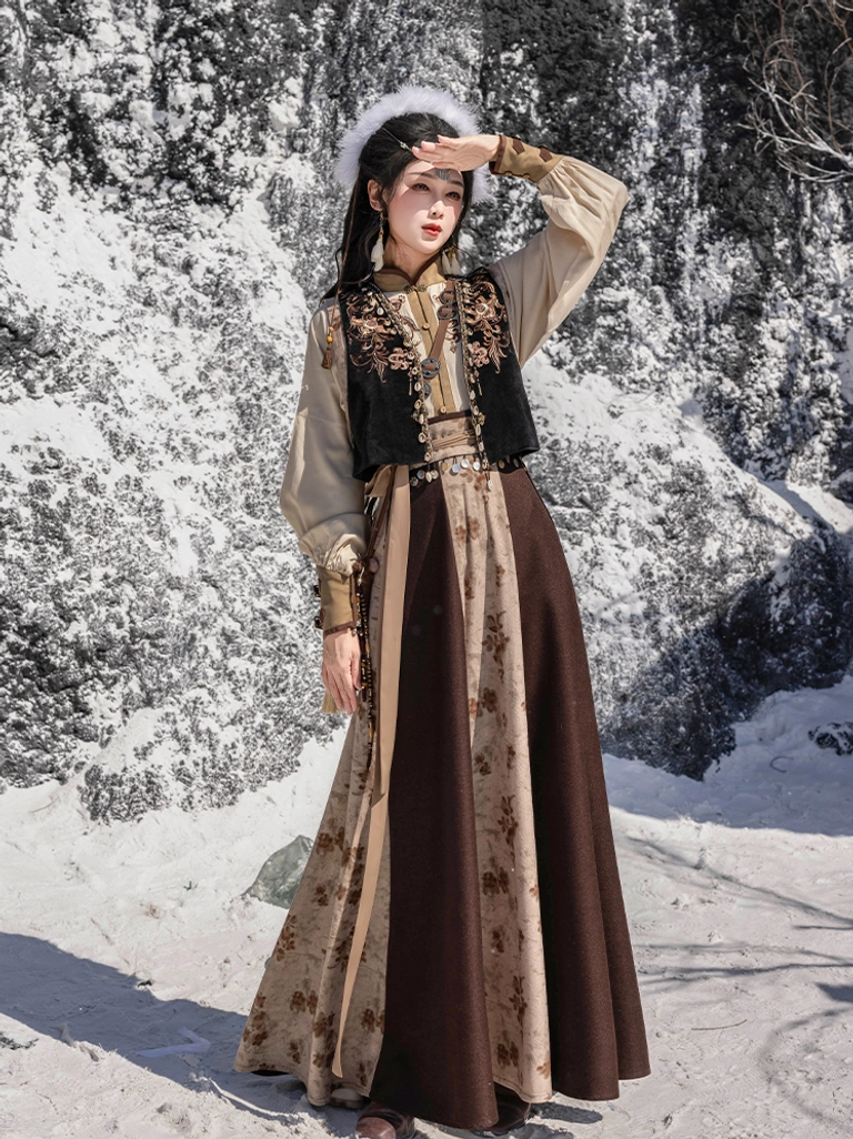 Front view of a frontier-inspired Tang Dynasty Hanfu set showing the floral embroidered vest decorative waist belt and layered wrap skirt in a winter outdoor scene