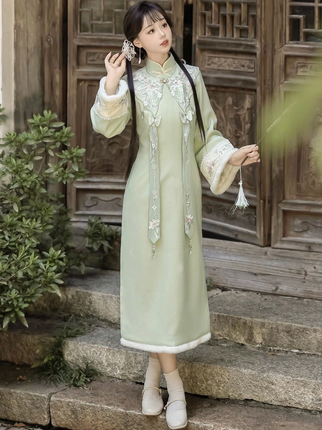 Three-quarter front view of bean green modern cheongsam dress with Mandarin collar, embroidered cloud shoulder detail, and plush trim