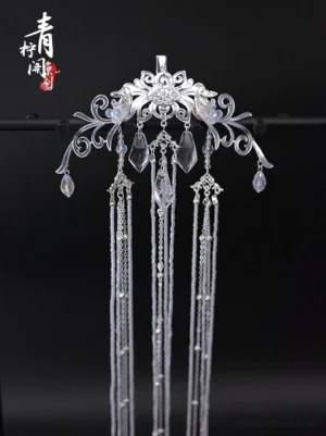 Close-up of an antique-inspired Chinese back hair pin showing intricate carved floral filigree, clear crystal accents, and detailed hanging chain tassels
