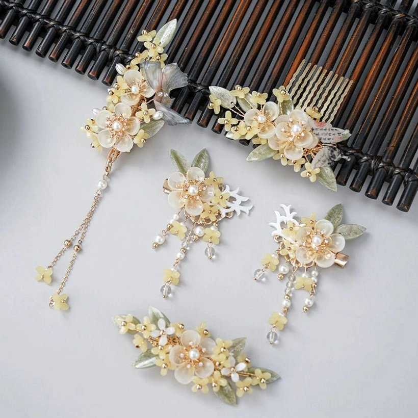 Full Drunk Osmanthus Hanfu hair accessories collection with creamy yellow flowers, green foliage, pearl details, gold-tone ornaments, and tassel pendants on a dark wooden background