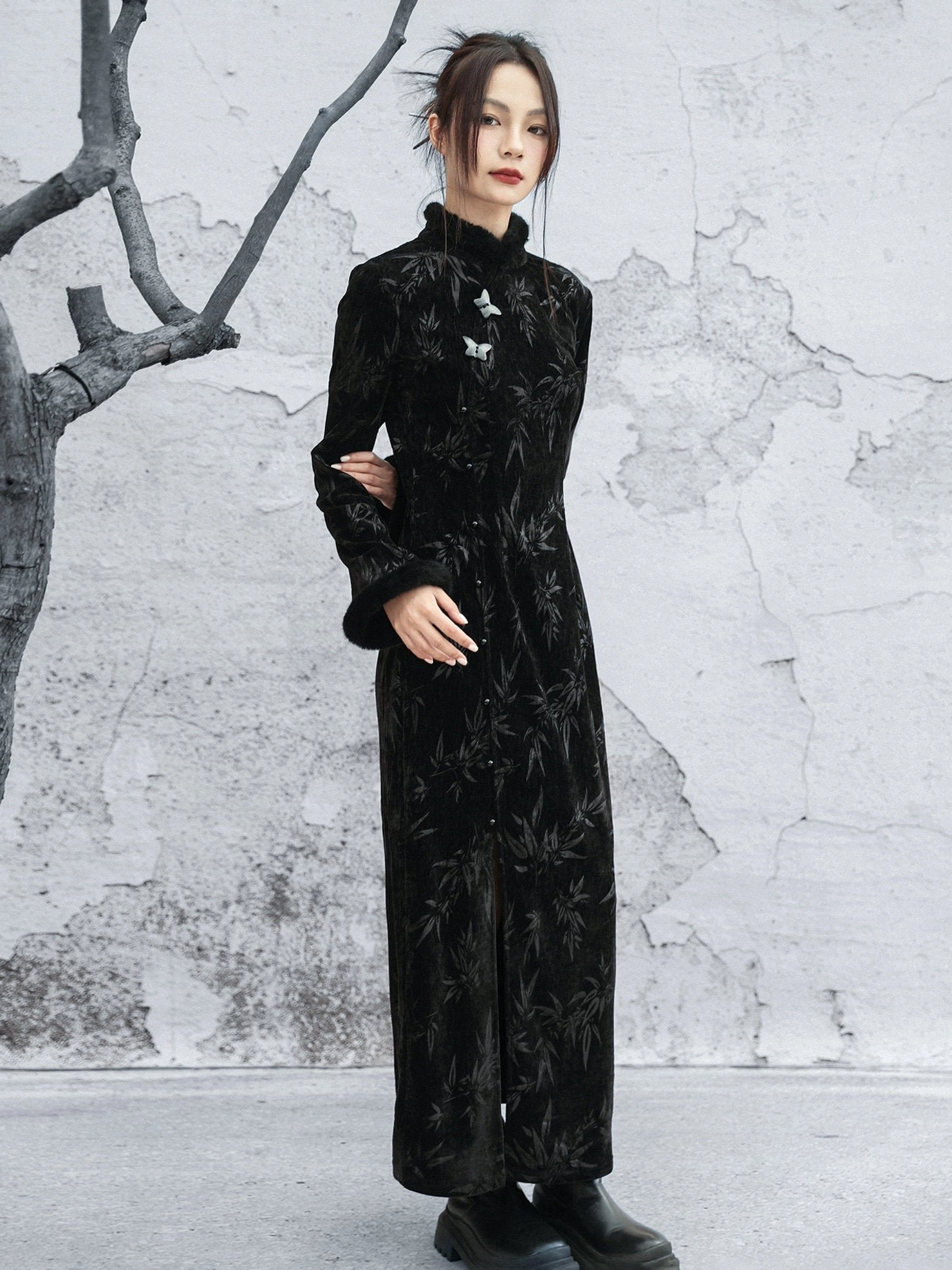 Full-length black bamboo jacquard velvet cheongsam dress shown from the side with fitted waist, floor-length hem, frog button collar details, and black boots