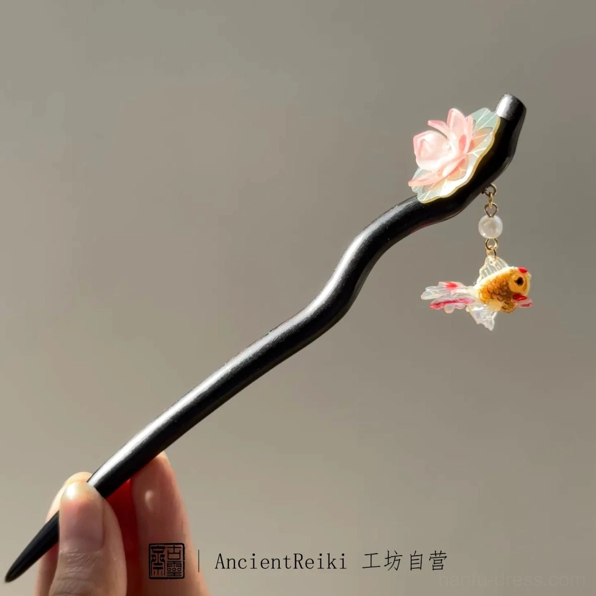 Full-length handmade Chinese hair stick with a curved black wooden pin, pink lotus decoration, and traditional golden goldfish charm