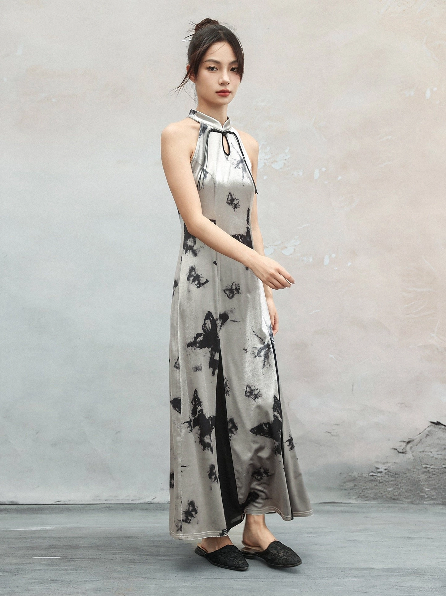 Full-length front view of a silver modern Hanfu butterfly cheongsam dress with slim floor-length silhouette, sleeveless halter collar, and scattered black ink-style motifs