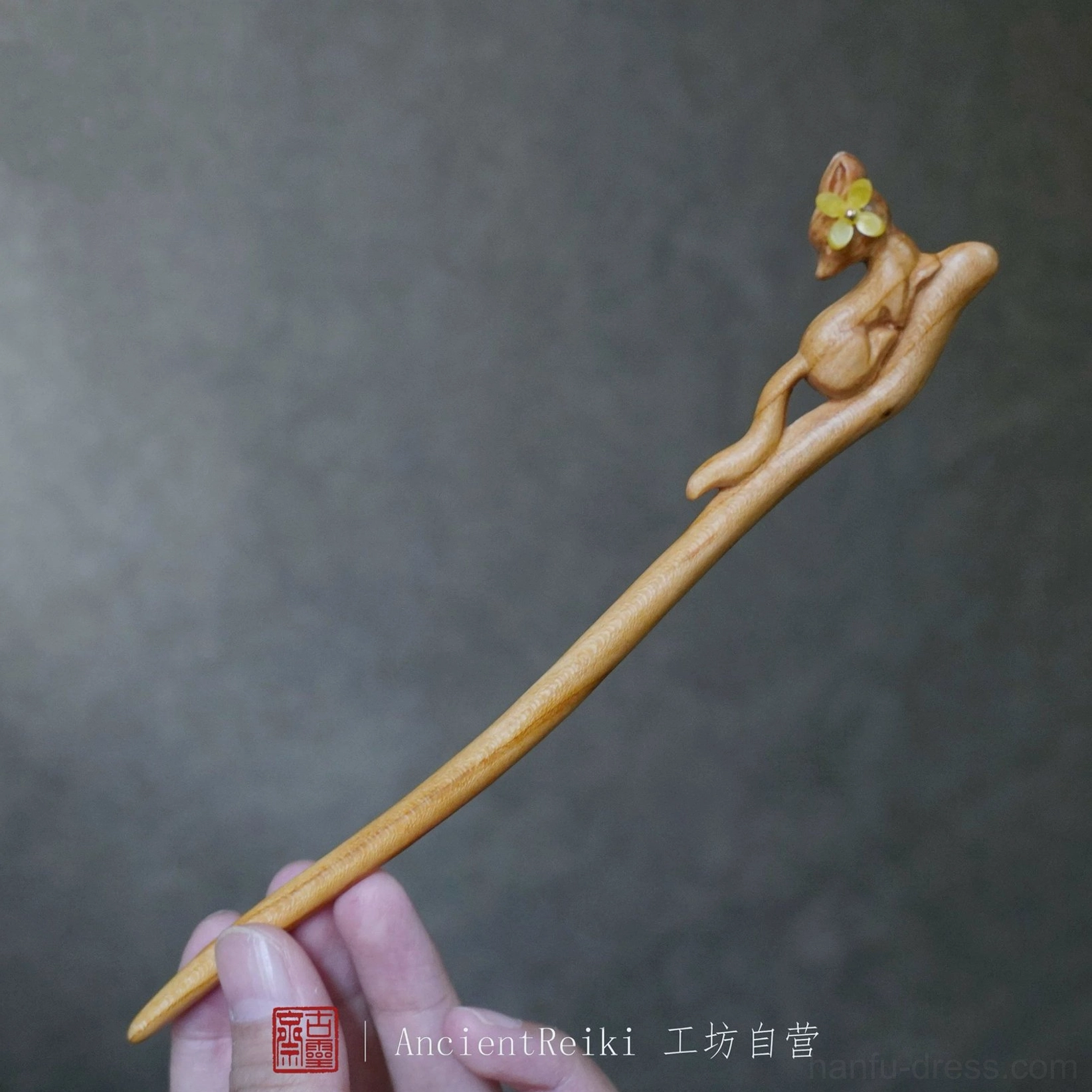 Full-length light brown wooden fox hair stick held by hand to show its slender shaft and decorative Hanfu hair accessory design