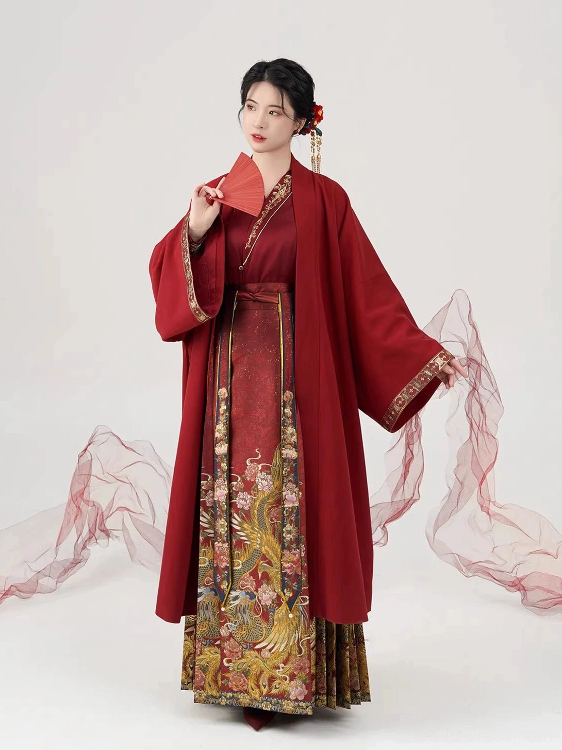 Full red Ming-style wedding Hanfu ensemble shown from the side with flowing long overcoat, embroidered sleeve trim, and Mamian skirt