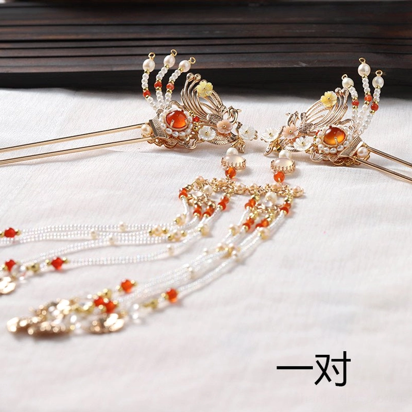 Full pair of matching phoenix tassel Chinese hair sticks with gold tone metal red and white bead accents on dark wooden background