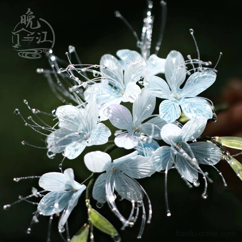 Full view of a delicate blue Chinese flower hair stick with gradient petals matching green leaves and sparkling droplet decorations