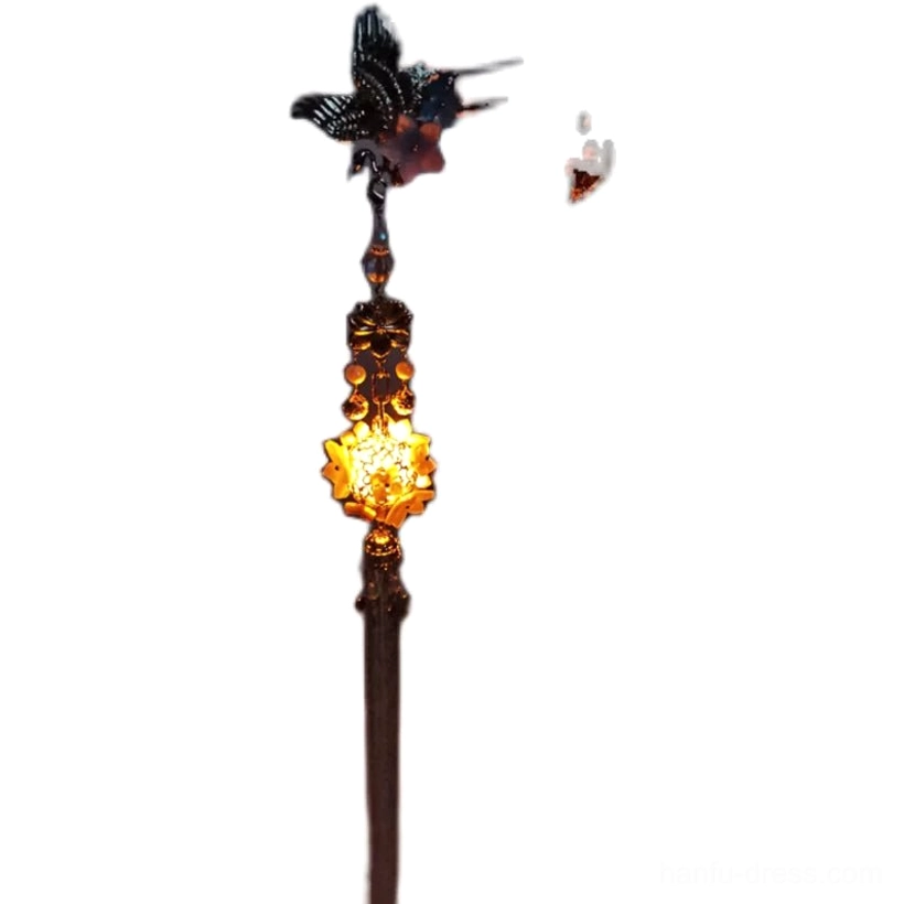Full studio view of traditional Chinese hair stick featuring a dark crane topper, gilded glowing lantern pendant, decorative beads, and tassel