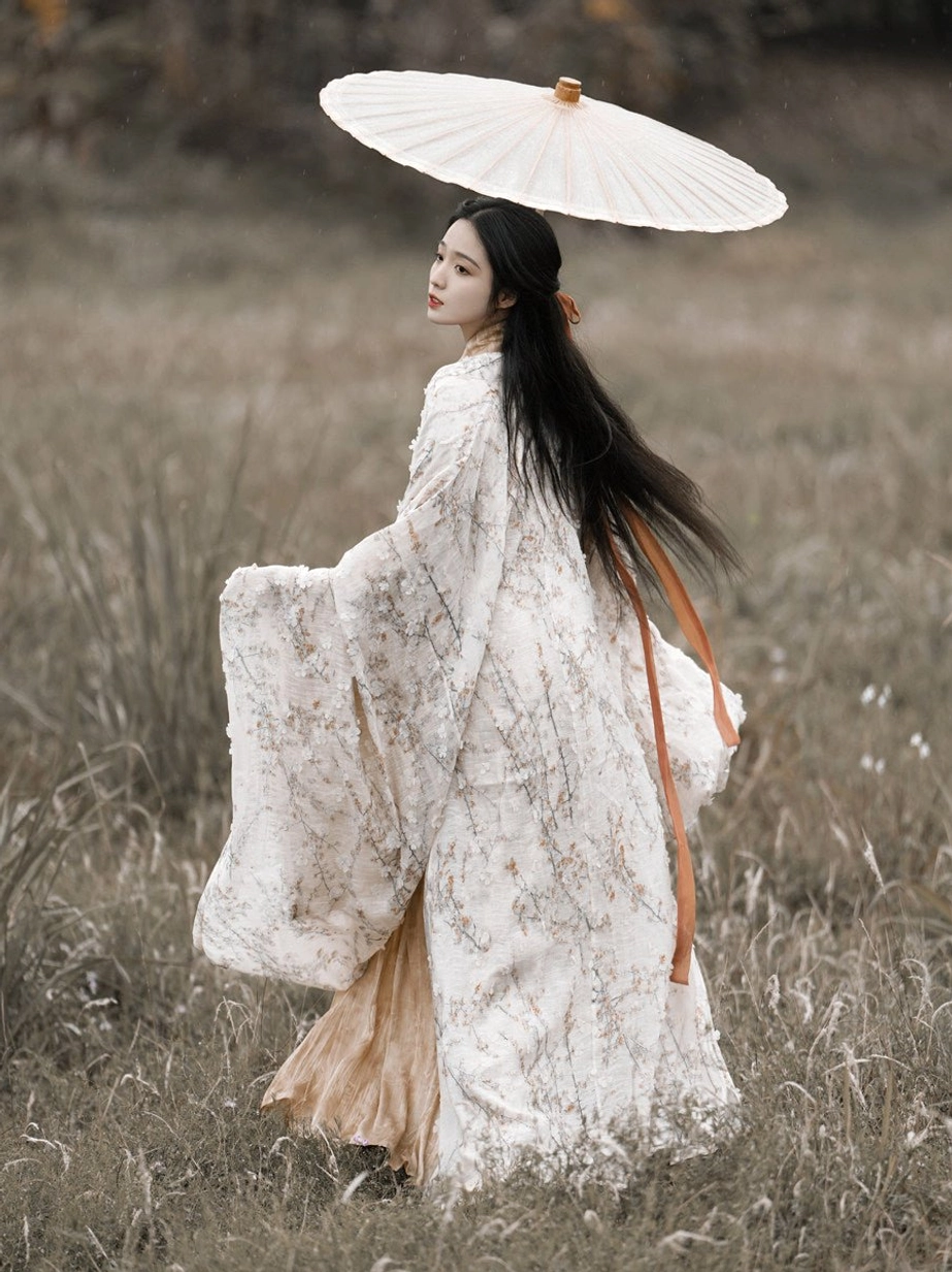Back three-quarter walking view of Fusheng Ruomeng Wei Jin Hanfu with floral outer robe beige gown orange sash and flowing sleeves