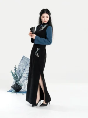 Side view of dual-tone embroidered Chinese cheongsam dress showing the elegant high side slit, long fitted sleeves, floral embroidery, black folding fan, and formal styling