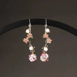 Garden vine floral Chinese earrings displayed on a black stand with pink enamel flowers white faux pearls and layered flower pendants