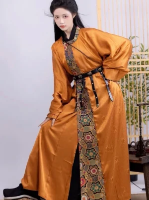 Ginger Tang Dynasty round collar Hanfu robe for men and women shown in a three-quarter standing view with black cuffs, floral brocade trim, and waist belt