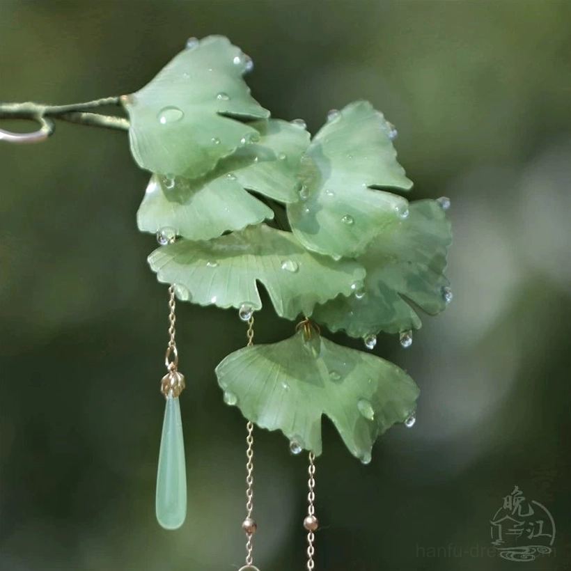 Front angled view of green layered ginkgo leaf traditional Chinese hair stick with dew-drop accents and flowing tassels