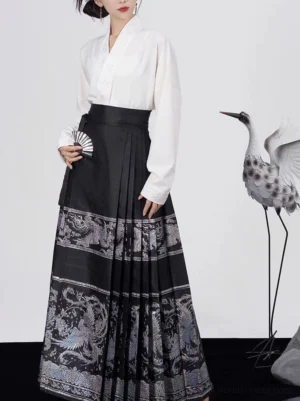 Three-quarter view of black silver brocade Mamianqun horse face skirt styled with a white cross-collar Hanfu blouse and folding fan