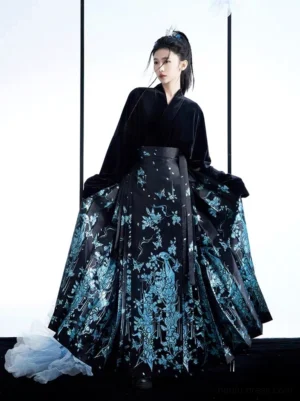 Modern Ming style mamianqun Hanfu complete set shown in a three-quarter front view with a black velvet cross-collar top and flowing black horse face skirt decorated with blue floral and bird motifs