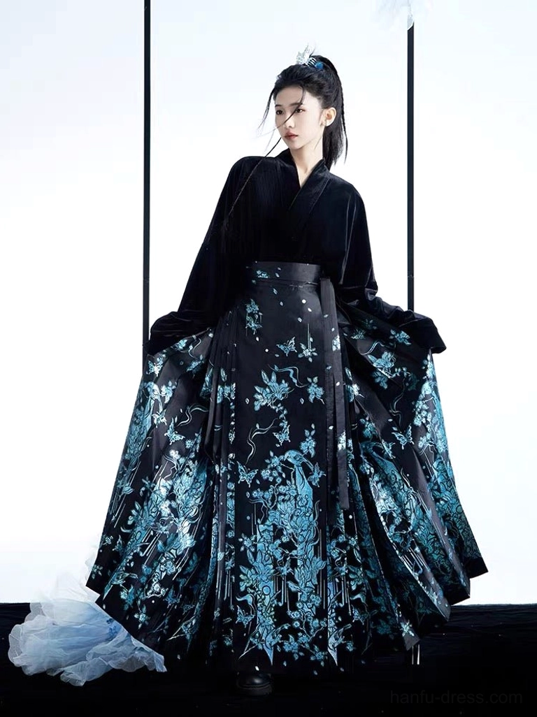 Modern Ming style mamianqun Hanfu complete set shown in a three-quarter front view with a black velvet cross-collar top and flowing black horse face skirt decorated with blue floral and bird motifs