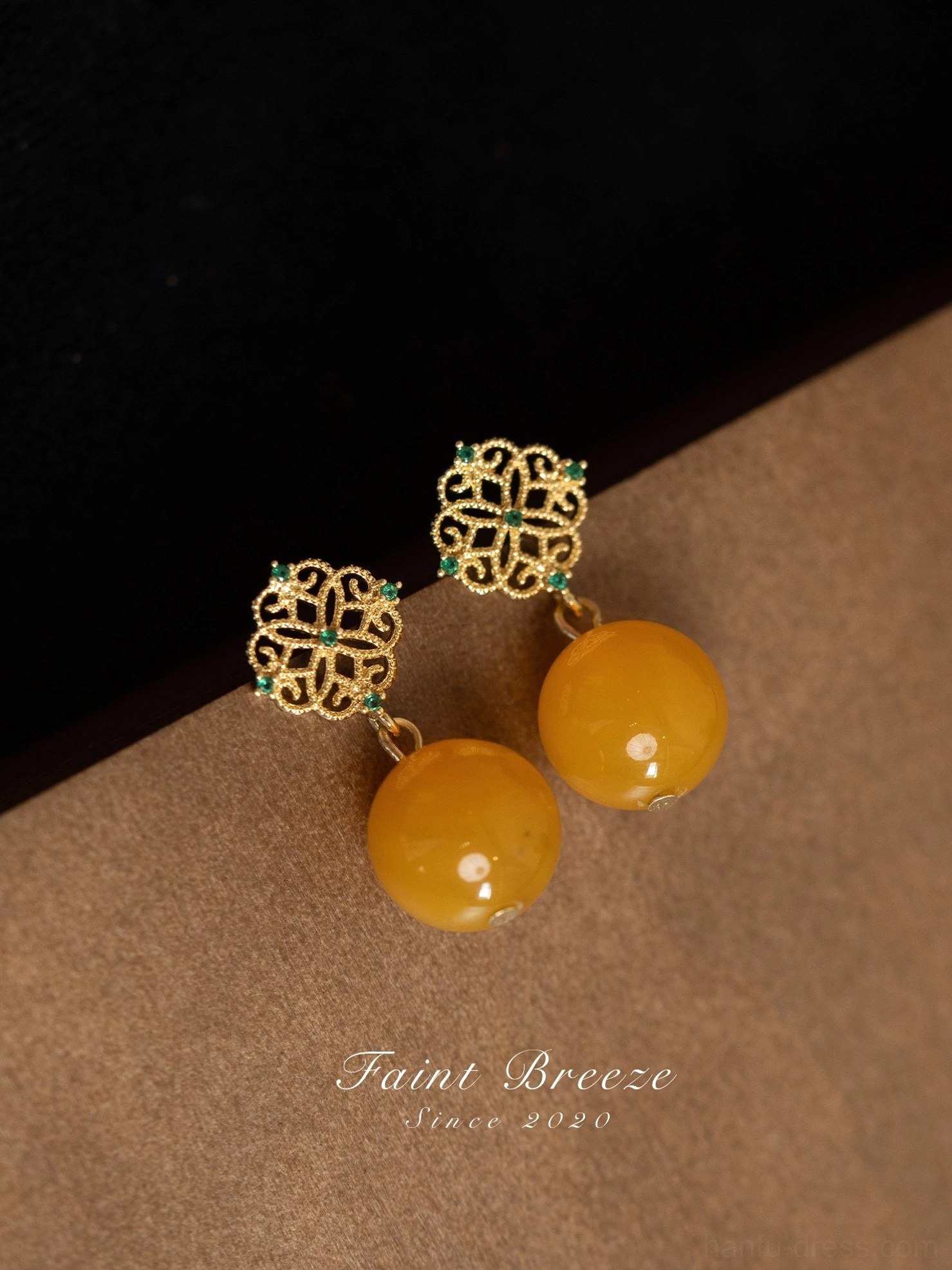 Close-up of elegant Chinese earrings featuring intricate gold flower filigree, glossy round amber-colored beads, and a refined vintage East Asian jewelry design