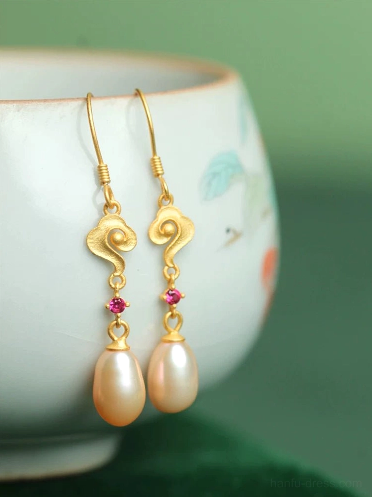 Golden auspicious cloud teardrop pearl earrings for Hanfu displayed beside hand-painted porcelain on dark green velvet fabric