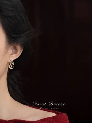 Woman wearing golden bamboo gourd pearl Chinese earrings, an elegant Hanfu jewelry accessory shown in side profile