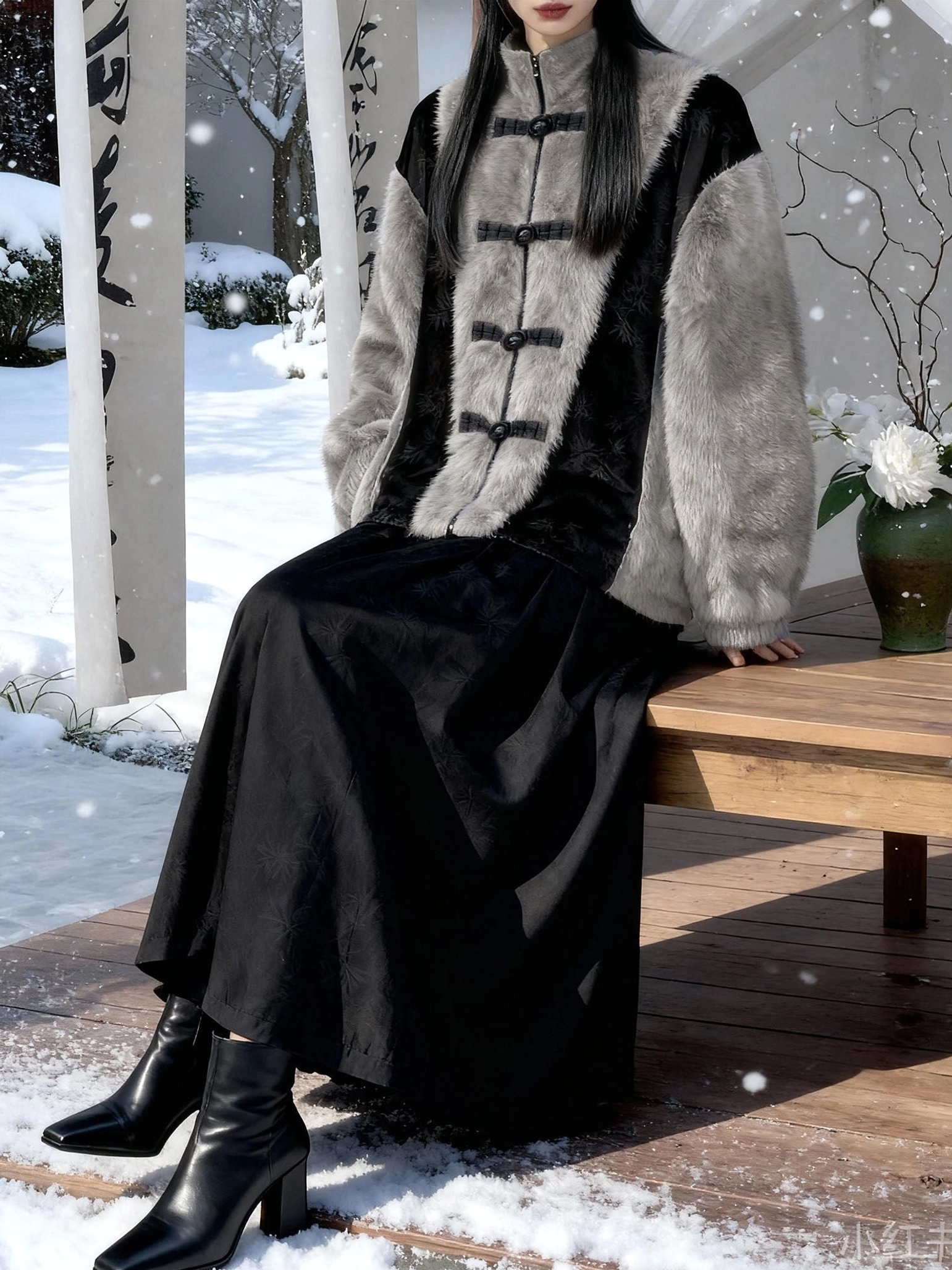 Seated model wearing a Golden Bamboo Leaf faux fur modern hanfu jacket with a black skirt and ankle boots in a snowy Chinese-style garden
