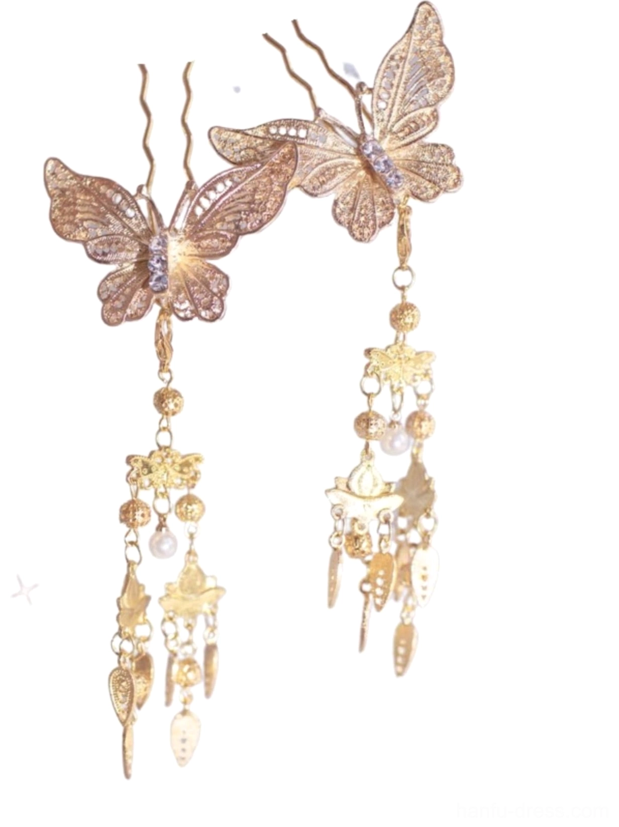 Flat lay of a pair of golden butterfly hair pins with filigree butterfly designs, pearl-like tassels, and decorative metal charms