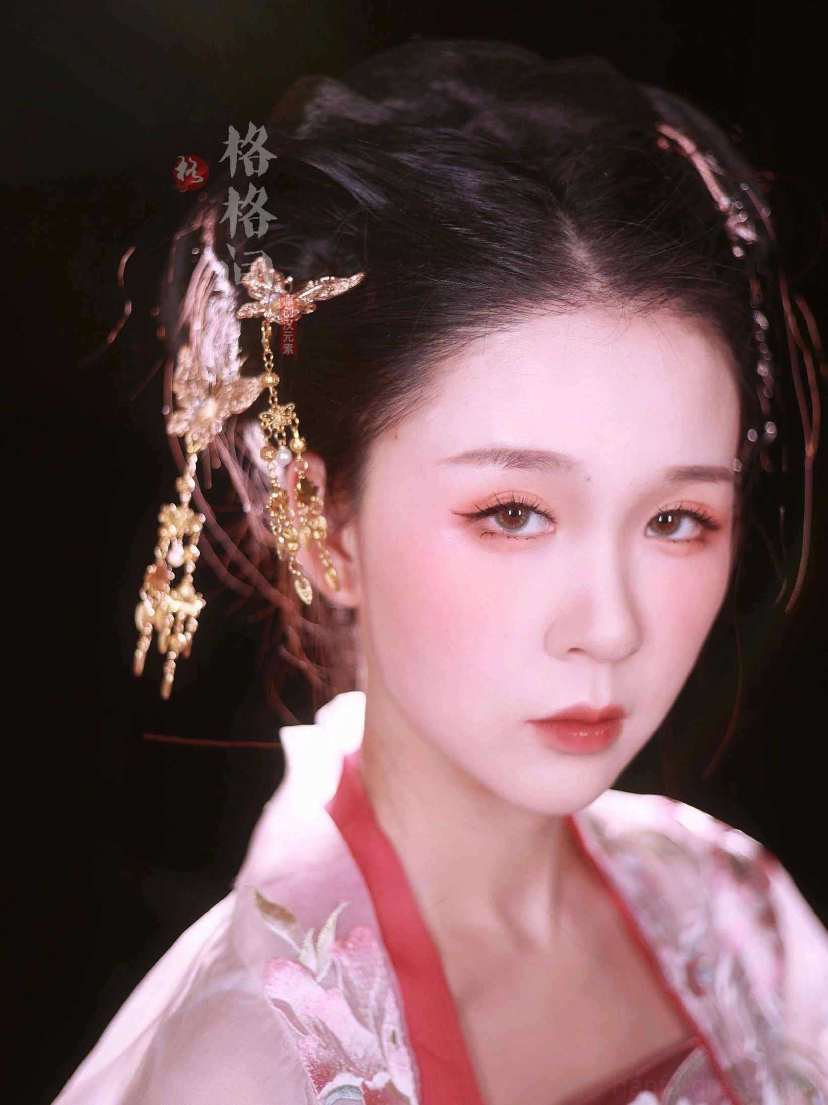 Front portrait of a woman in pink Hanfu wearing multiple golden butterfly tassel hair pins secured around a classic traditional hair bun