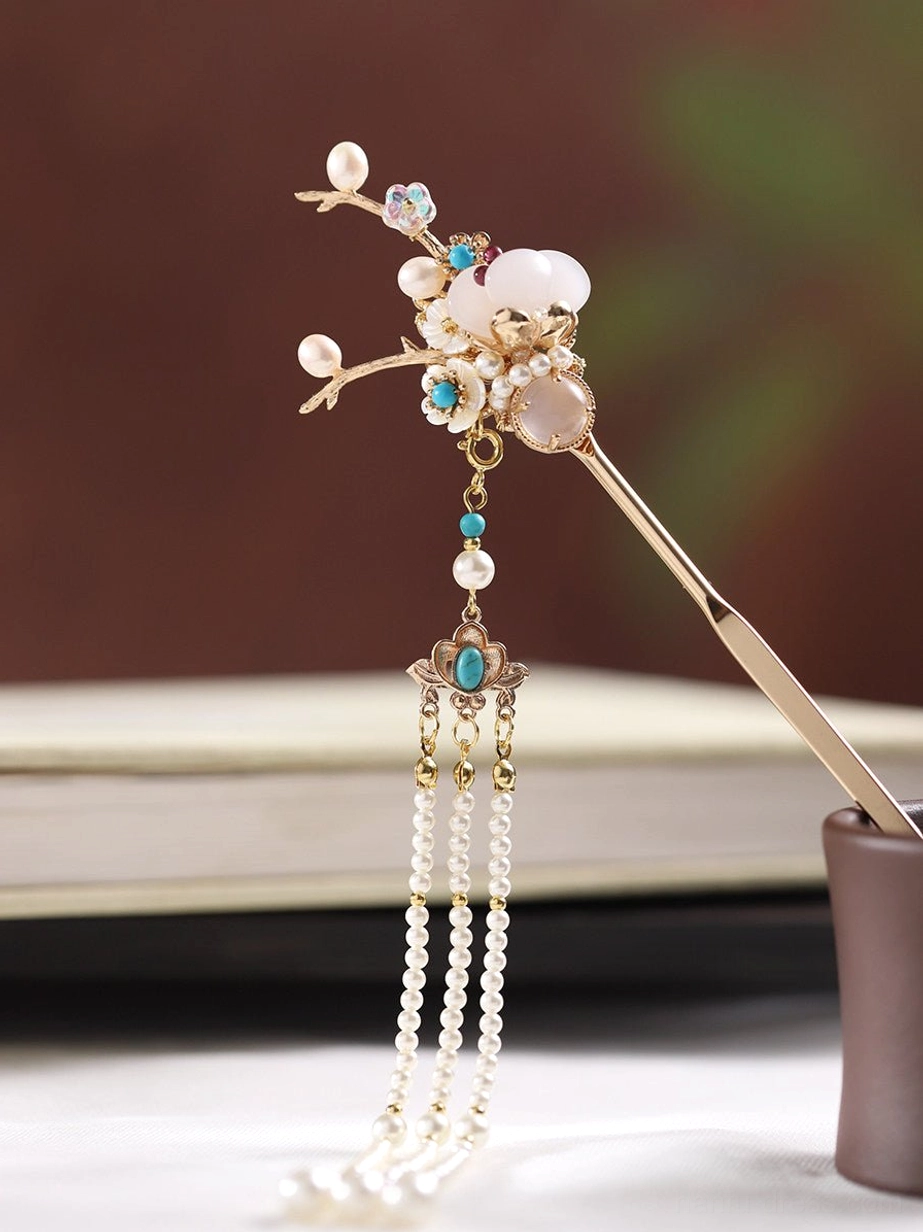 Detailed angled view of a single golden Chinese hair stick decorated with milky white beads, turquoise-toned ornaments, and a long hanging pearl tassel