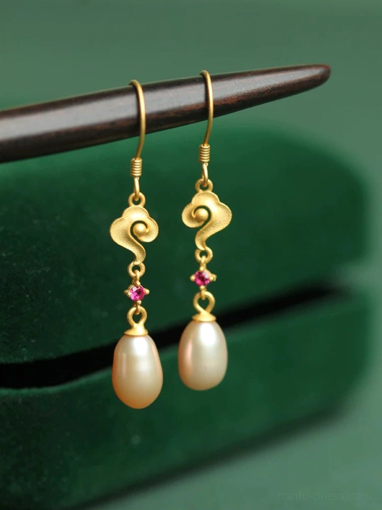 Golden cloud pearl drop Hanfu earrings with matte gold auspicious cloud charms, rose-red accents, teardrop pearls, and 925 silver hook ear wires displayed on green velvet