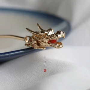 Golden dragon Chinese hair stick close-up with detailed carved dragon head and red gemstone on ceramic plate