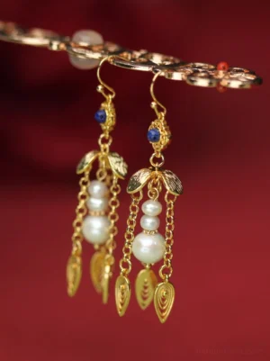 Close-up of golden gourd Hanfu tassel earrings with pearl strands, textured gold leaf pendants, blue bead accents, and ornate metalwork