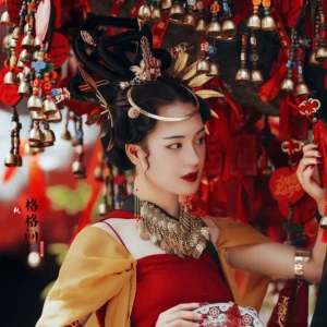 Model wearing golden leaf Hanfu hair pins with an elaborate traditional Chinese hairstyle and red yellow Hanfu near a wishing stall