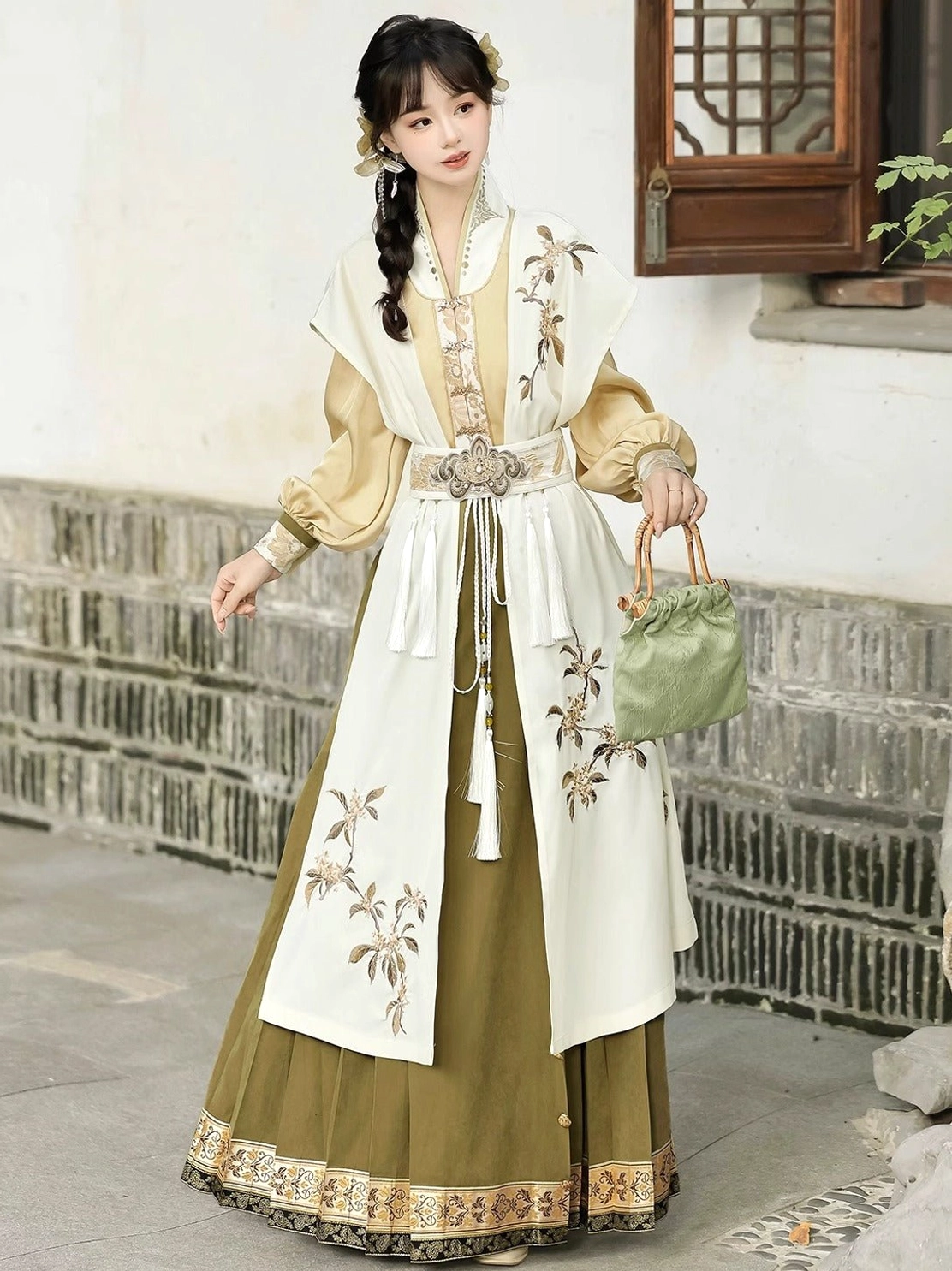 Detailed three-quarter side view of golden osmanthus Hanfu with metal tassel waist ornament and pleated olive green mamianqun horse face skirt