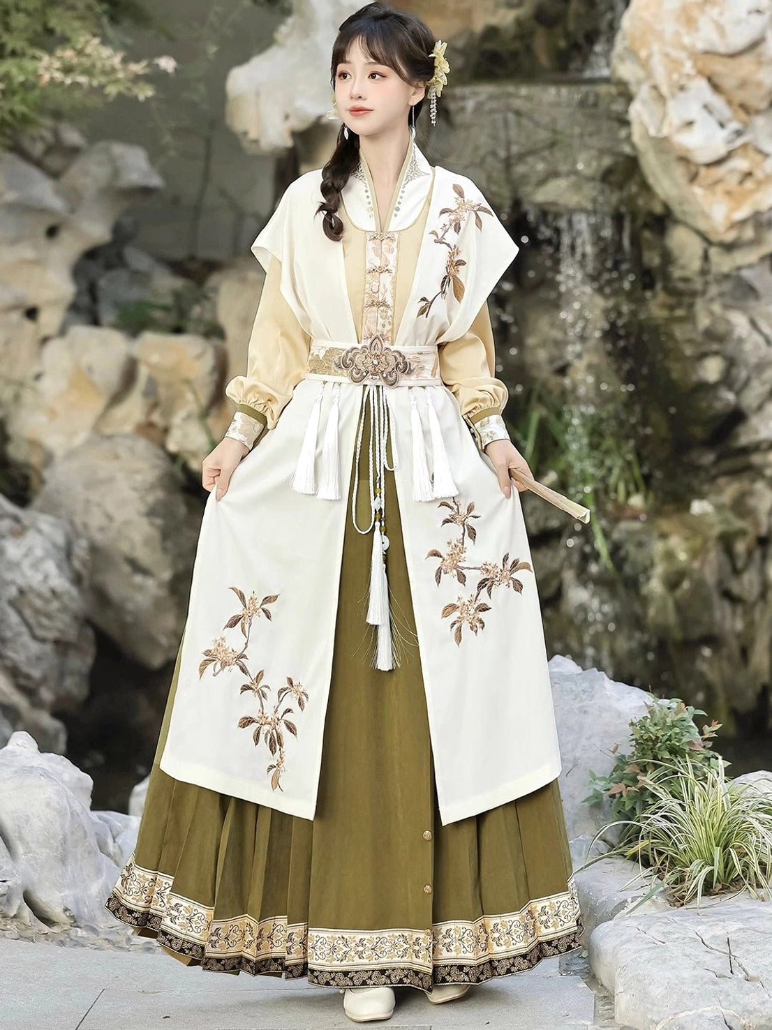 Golden osmanthus modern Ming Dynasty Hanfu set with cream embroidered vest, mustard top and olive green mamianqun horse face skirt in a Chinese garden