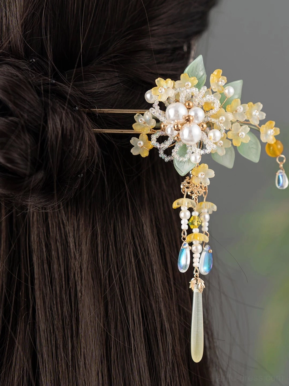 Golden osmanthus tassel Chinese hair stick worn in a dark braided traditional Hanfu hairstyle from the back