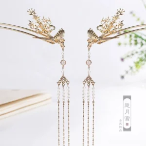 Pair of golden phoenix tassel hairpins with carved floral details pearl-like chains and decorative beads displayed on a light background