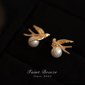 Golden swallow pearl stud earrings for Hanfu with smooth white pearl accents displayed on a black velvet jewelry tray