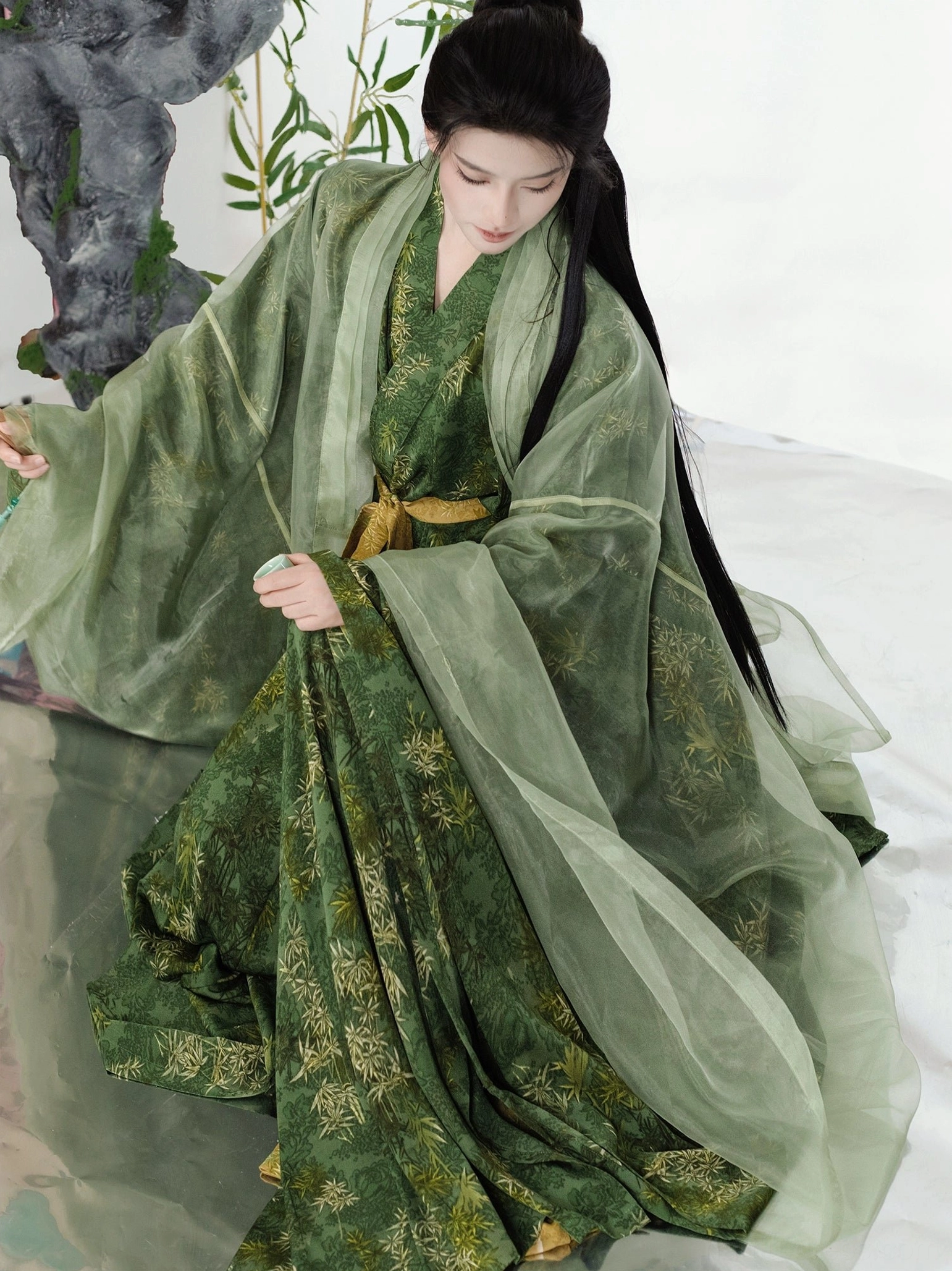 Three-quarter side view of a green Song Dynasty Hanfu bamboo leaf print outfit showing the sheer flowing outer beizi, cross-collar robe, golden waist belt, and traditional styling