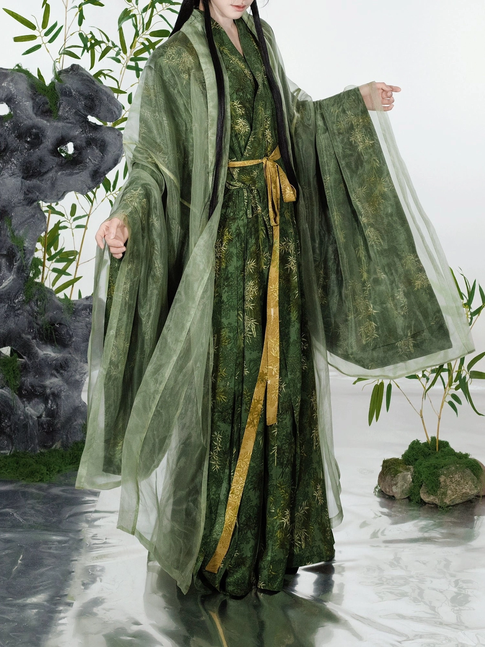 Full-body side view of a female model in a green bamboo print Song Dynasty Hanfu set with oversized wide sleeves, sheer cardigan, yellow sash, and layered robe