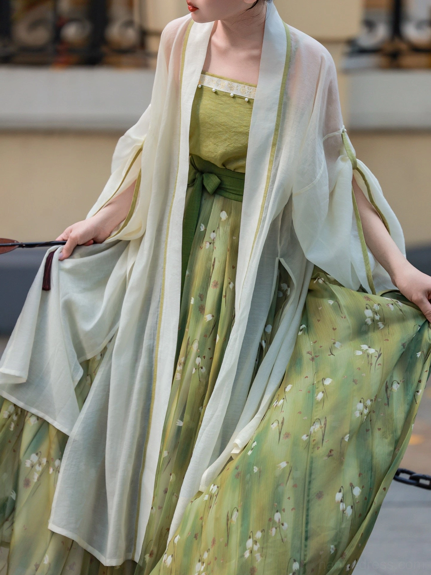 Close view of green floral Song Dynasty Hanfu showing textured camisole, botanical pleated skirt and flowing sheer cardigan