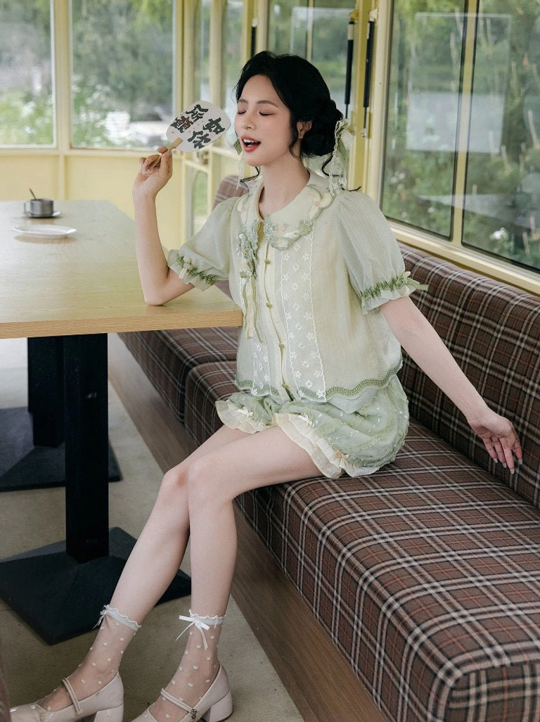 Side view of a matching green summer Hanfu two-piece outfit with sheer embroidered puff sleeves, ruffled blouse hem, and layered bloomer trim