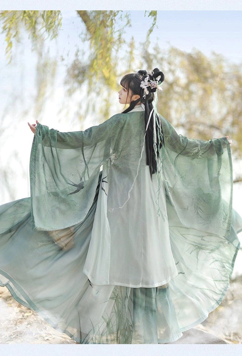 Back view of green Swallow Flight Song Dynasty Hanfu showing layered gradient chiffon skirt, translucent flowing outer robe, swallow prints, and traditional braided hairstyle