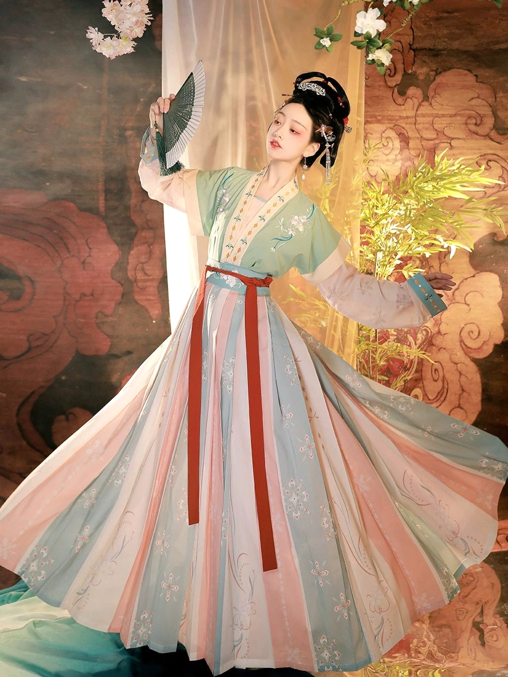 Side view of green Tang Dynasty Hanfu beizi qiyao ruqun with flowing pastel pleated skirt, red sash, and green folding fan